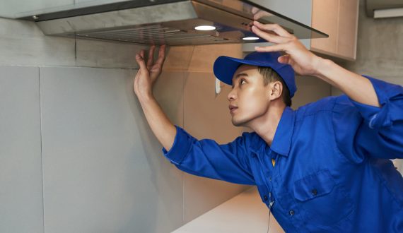 Young Vietnamese technician installing extractor hood in kitchen